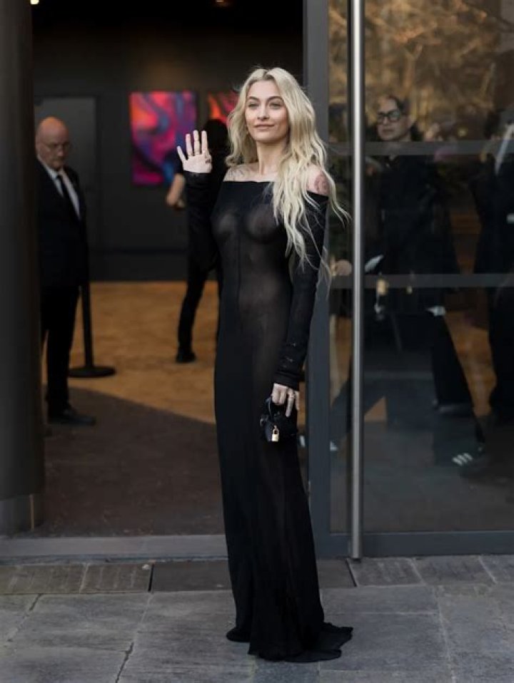 Paris Jackson is seen wearing a peace sign necklace and smiling.